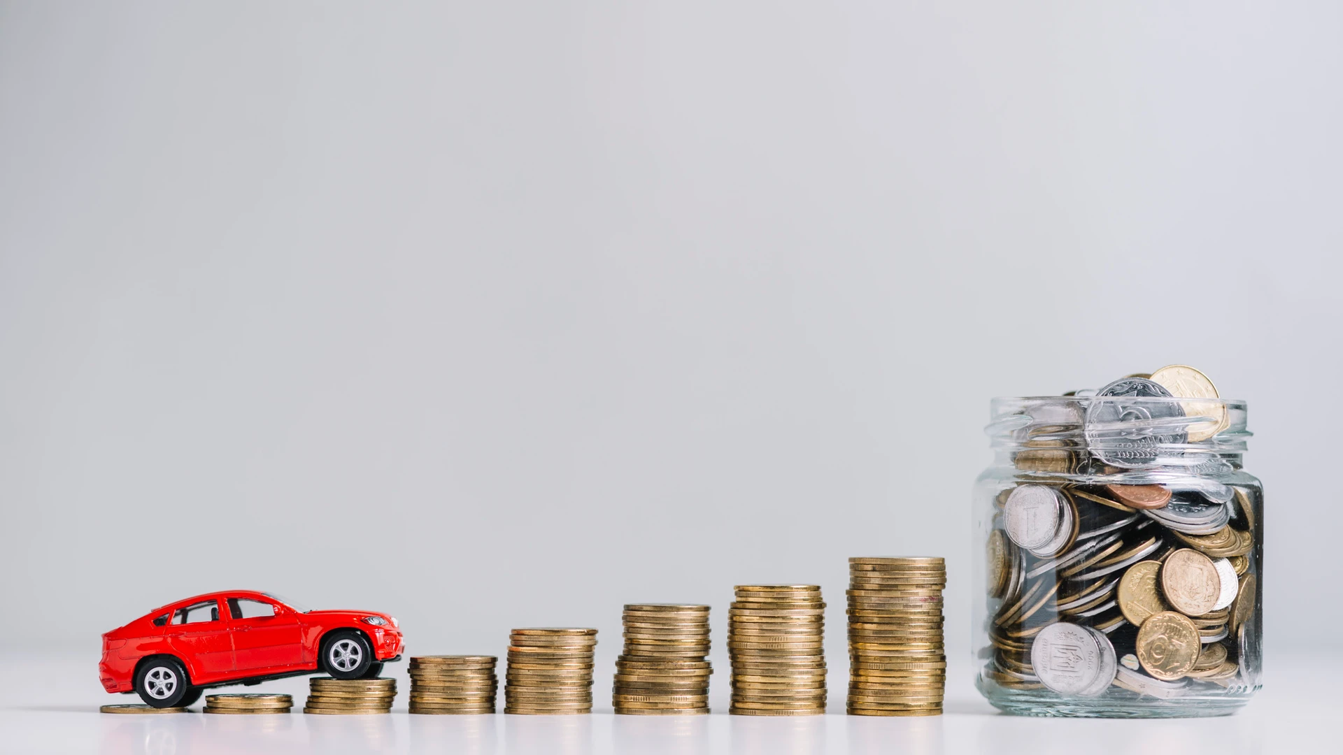Car driving over increasing stacked coins near glass jar