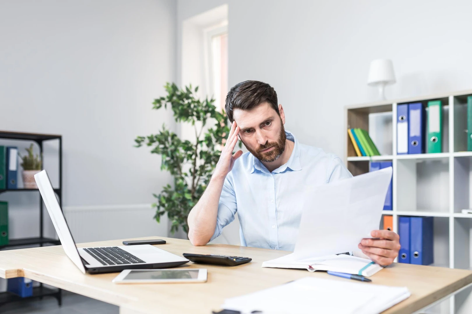 Frustrated and worried businessman looks at bad performance of the company on the documents an evil man holds in his hands fi