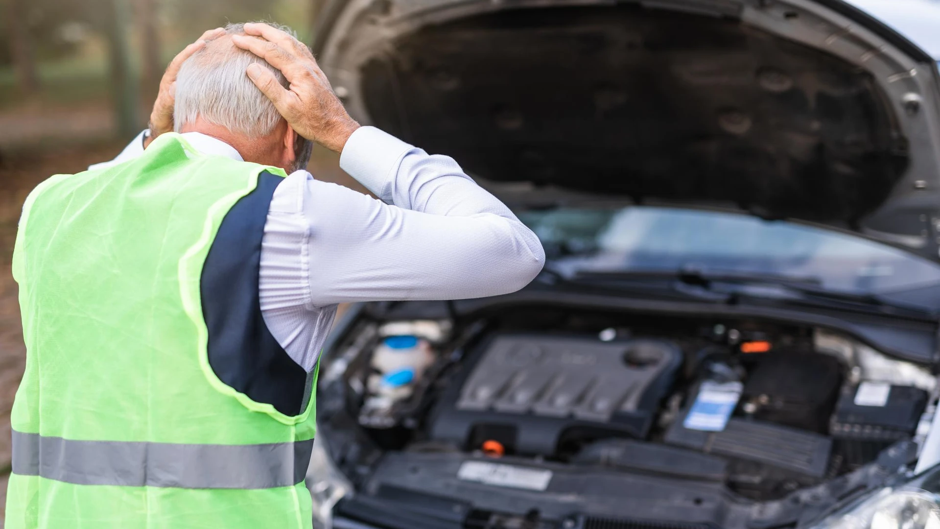 Car breakdown. Senior man looking at car engine and trying to repair it.
